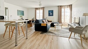 A modern living room with a sofa, coffee table, and dining area. - ★ Cosy Apartment Near Disneyland Paris ★ (Serris)