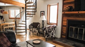 A cozy living room with a fireplace, a staircase, and a dining area. - Silverthorn Skiing & Hiking with Community pool/hot tub/Sauna. (Silverthorne)