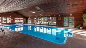 An indoor swimming pool with wooden ceiling and walls, surrounded by chairs and potted plants. - Silverthorn Skiing & Hiking with Community pool/hot tub/Sauna. (Silverthorne)