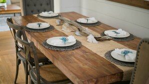 A wooden dining table with woven placemats, white plates, and napkins. - The Robin house - Close to Everything! (Mount Pleasant)