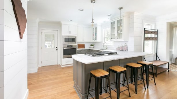 A modern kitchen with white cabinetry, a large island with bar stools, stainless steel appliances, and pendant lighting. - The Robin house - Close to Everything! (Mount Pleasant)