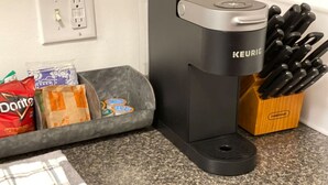 Une cuisine équipée d’une machine à café Keurig, d’un bloc à couteaux et d’un plan de travail sur lequel sont posés des sachets de collations.