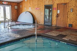 A hot tub area with a wooden wall, a pool, and a no-jumping sign.