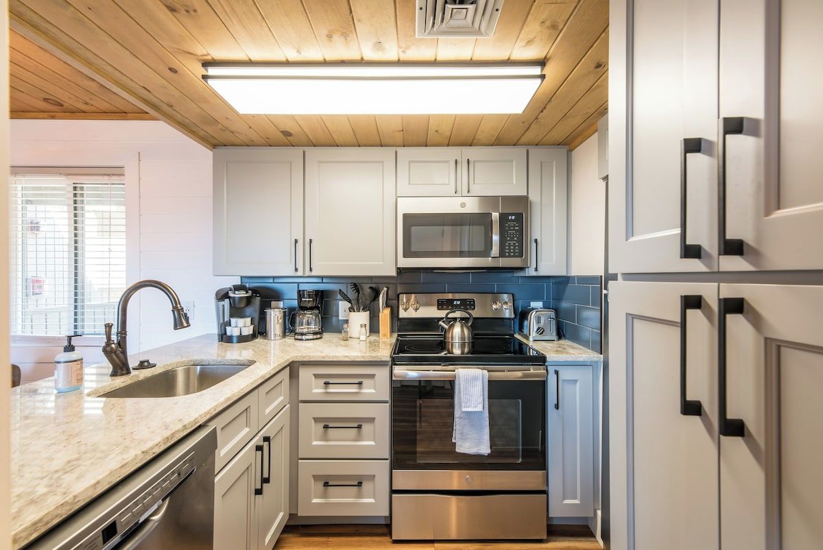 A modern kitchen with stainless steel appliances, a double sink, and light blue cabinets.