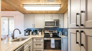Eine moderne Küche mit Edelstahlgeräten, weißen Schränken und einer Holzbalkendecke.