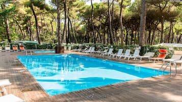 Een buitenzwembad, ligstoelen bij het zwembad