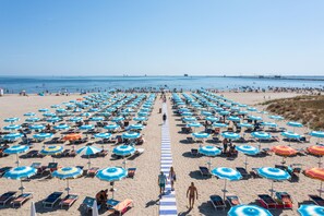 A beach with rows of umbrellas and sun loungers. - Club Del Sole Marina Romea Easy Camping Village (Ravenna)