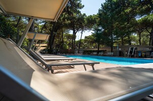 Una piscina al aire libre, sillones reclinables de piscina