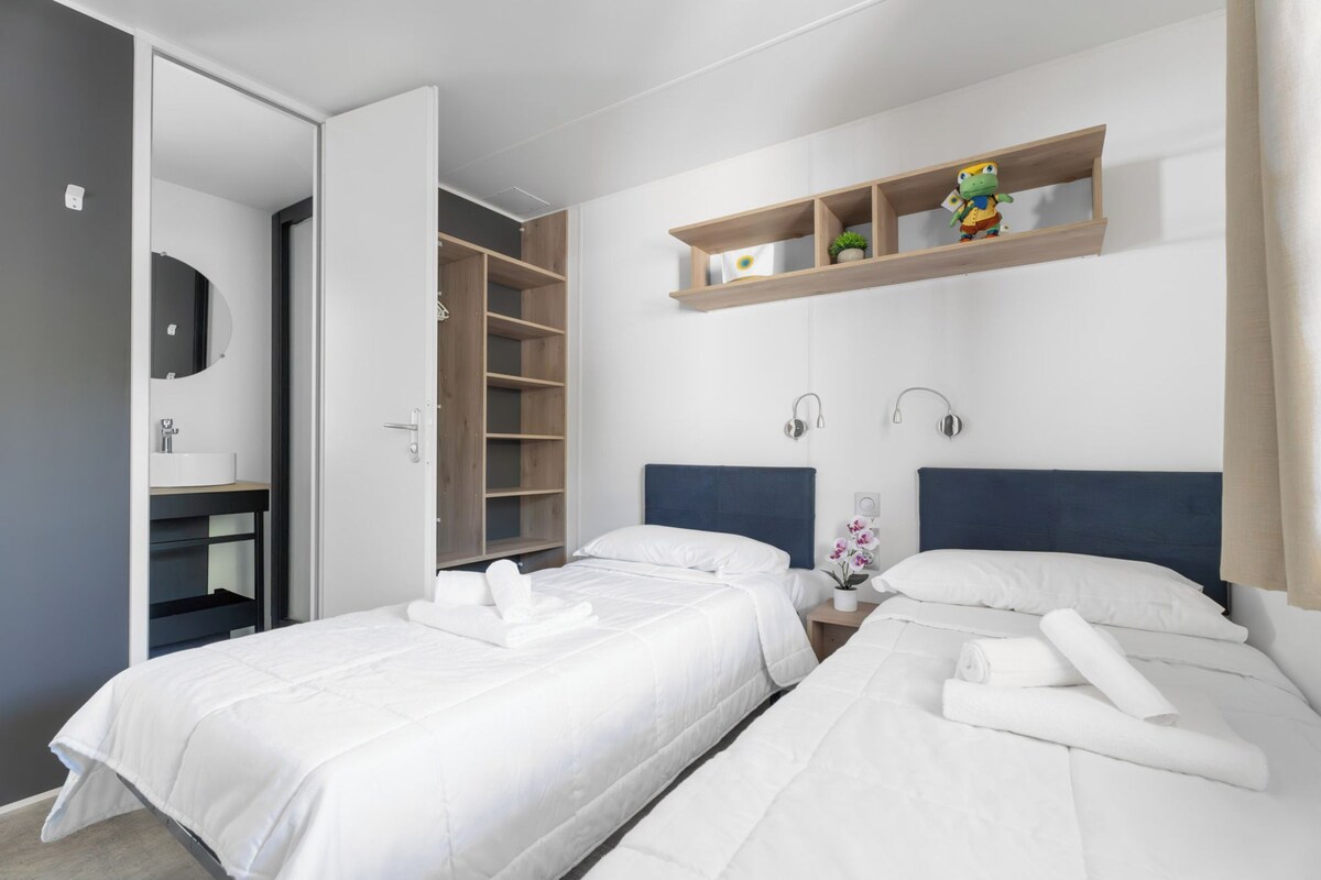 Une chambre d’hôtel avec deux lits, une armoire, un miroir et une étagère avec un jouet.