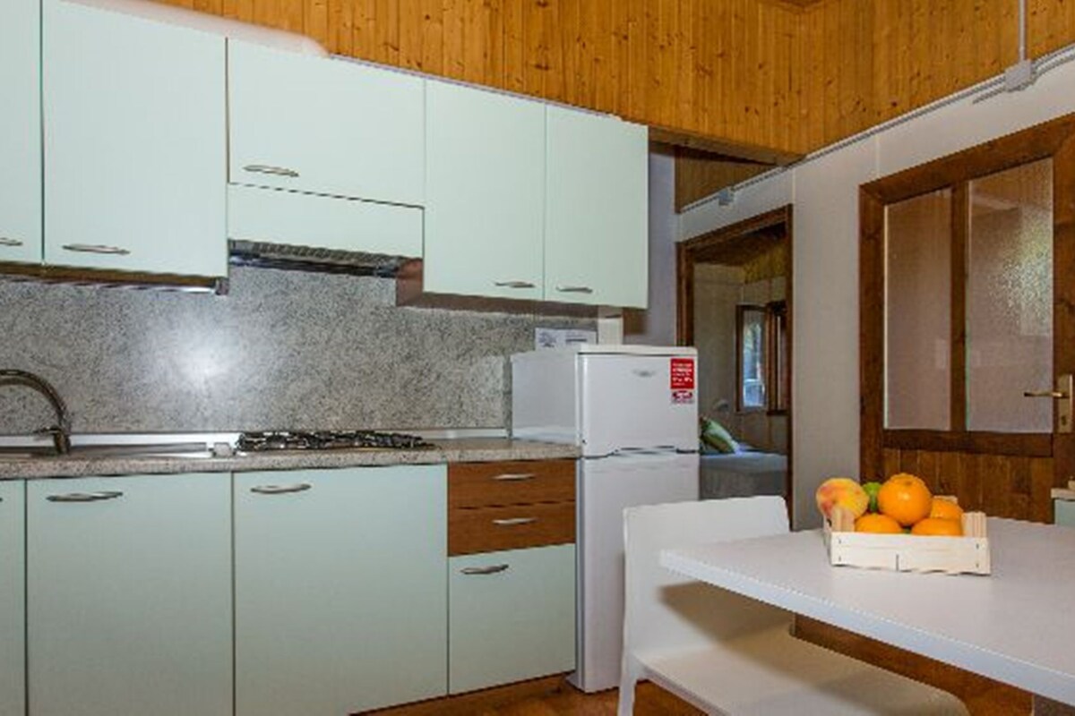 A kitchen with light green cabinets, a white countertop, a sink, and a refrigerator.
