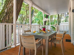 A covered outdoor dining area with a table set for two, surrounded by white railings and trees. - Club Del Sole Marina Romea Easy Camping Village (Ravenna)