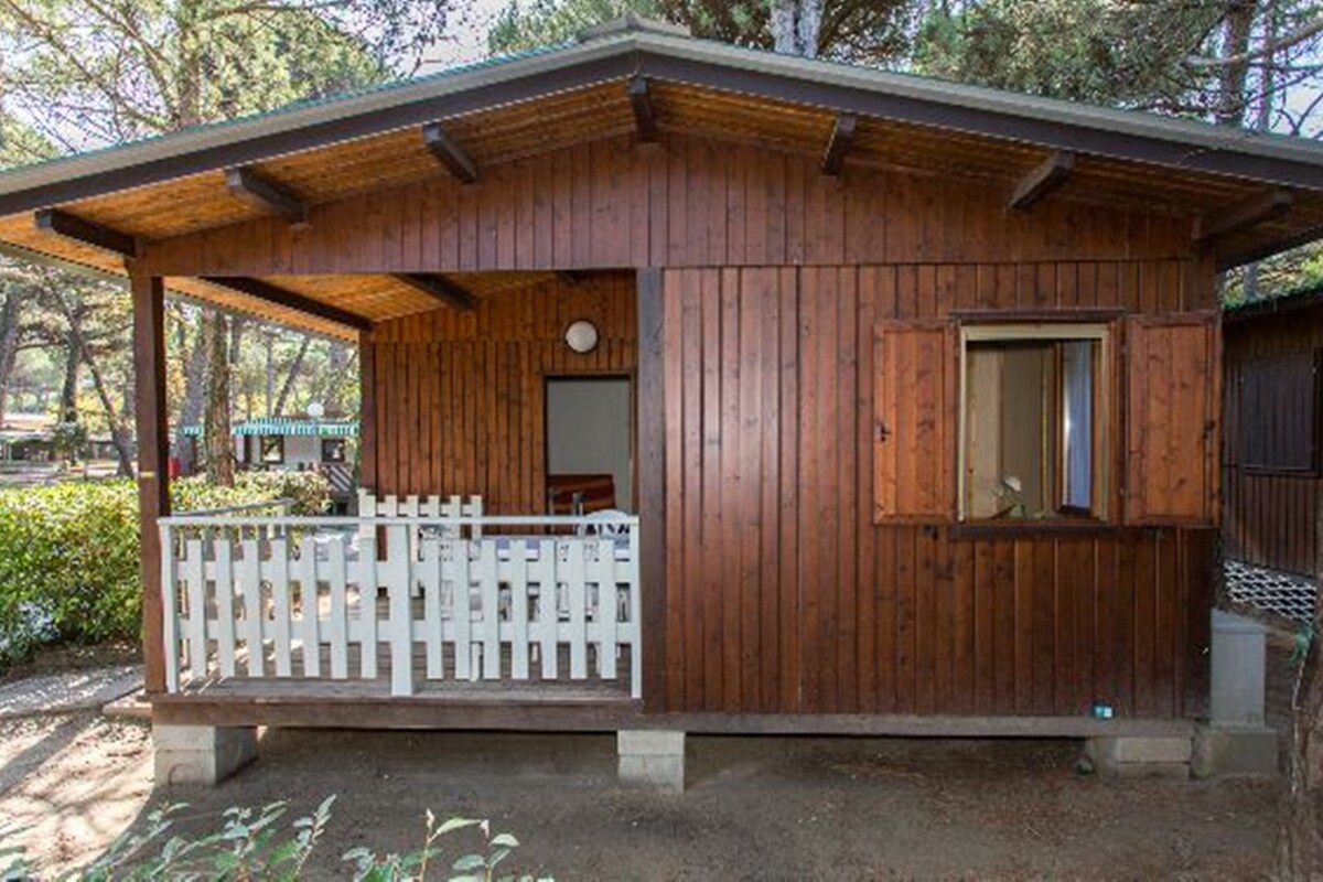 A wooden cabin with a porch, a small window, and a door.