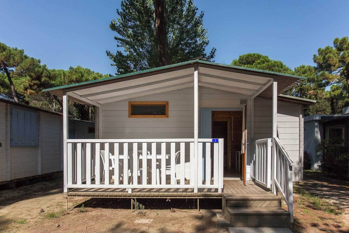 A single-story mobile home with a porch, a small window, and a door.