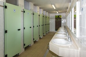 A row of green restroom stalls with white sinks and mirrors. - Club Del Sole Marina Romea Easy Camping Village (Ravenna)