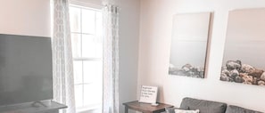 A living room with a flat-screen TV, a sofa, and two framed pictures on the wall. - LAKE HOUSE STYLE CONDO- Walk to the Marina, Sleeps 4! (Branson)
