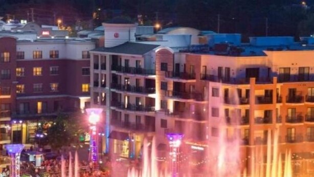 Un hotel con diversi piani, balconi e un'area fontana illuminata.