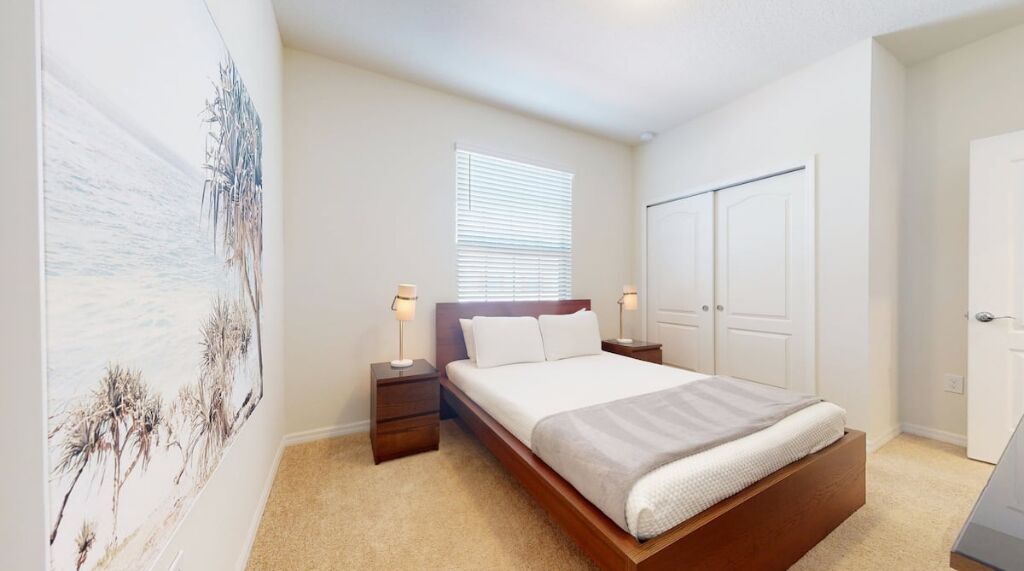 Un dormitorio con cama, mesitas de noche, ventana y armario.