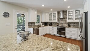 A modern kitchen with white cabinets, granite countertops, stainless steel appliances, and a built-in oven. - Kiawah Home with Private Salwater POOL & Short Walk to Beach! (Kiawah Island)