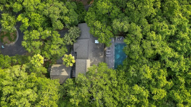 An aerial view of a house surrounded by dense trees, with a visible swimming pool and a paved driveway. - Kiawah Home with Private Salwater POOL & Short Walk to Beach! (Kiawah Island)