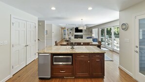 A kitchen with a granite countertop, built-in microwave, and wooden cabinets. - Kiawah Home with Private Salwater POOL & Short Walk to Beach! (Kiawah Island)