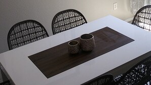 A dining area with a white table, black chairs, a decorative wall piece, and a chandelier. - VILLA Verde Surprise Stadium - Resort Living (Surprise)