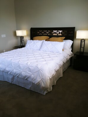 A neatly made bed with a geometric patterned bedspread, two bedside lamps, and a headboard with a geometric design.
