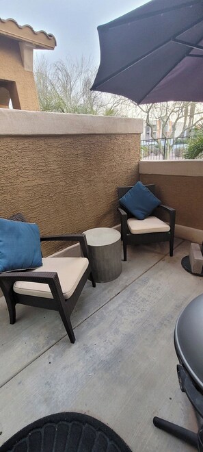 An outdoor patio area with wicker furniture, a round table, and a barbecue grill.