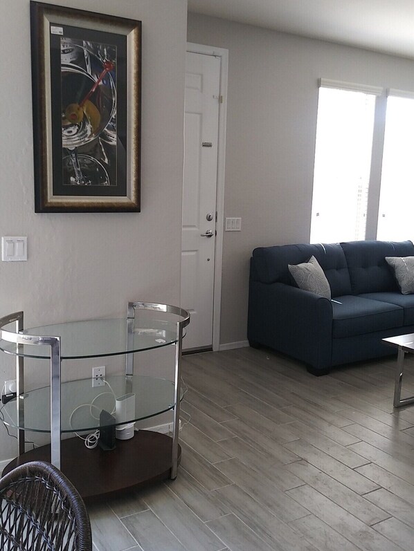 A living room with a glass table, a sofa, and a door.