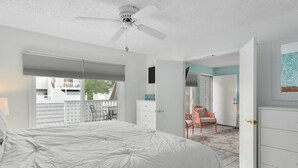 A bedroom with a large bed, a ceiling fan, a window with blinds, a door leading to another room, and a chair. - 2 BR 2 BA Unit W/Pool and Close to Northside Park (Ocean City)