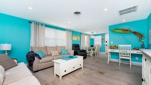 A living room with a sofa, coffee table, and dining area with chairs and a table. - Seaglass Inn at the Beach Shack  Just one block from the beach! (Englewood)