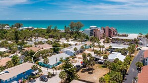 A coastal resort area with multiple buildings, including a prominent hotel with a red roof and a parking lot. - Seaglass Inn at the Beach Shack  Just one block from the beach! (Englewood)