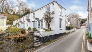 A narrow street lined with white houses, some with blue doors, and a stone wall on one side. - Fisherman's Cottage, a haven in Padstow old town (Padstow)