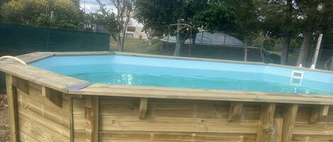 A wooden above-ground swimming pool with a ladder on one side.