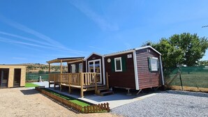 A small, single-story cabin with a wooden deck and a fenced yard. - Independent cabins Las Rosas (Pollos Valladolid)
