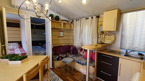 A compact living space with a kitchenette, a dining area, and a sleeping area with a sofa and a bed. - Independent cabins Las Rosas (Pollos Valladolid)