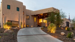 Un bâtiment moderne doté d’une allée incurvée, d’un éclairage extérieur et d’un aménagement paysager de style désertique.