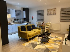 A modern living room with a yellow sofa, a coffee table, and a dining area with a table and chairs.