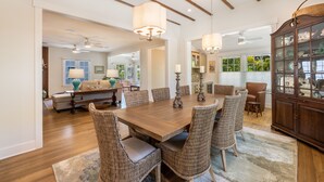 A spacious dining area with a large wooden table, wicker chairs, and pendant lighting. - Historic MamaDear House, Boca Grande Island w/private pool, 5min stroll to beach (Boca Grande)