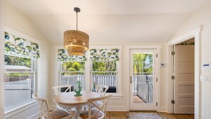 A dining area with a round table, white chairs, and a hanging light fixture. - Historic MamaDear House, Boca Grande Island w/private pool, 5min stroll to beach (Boca Grande)