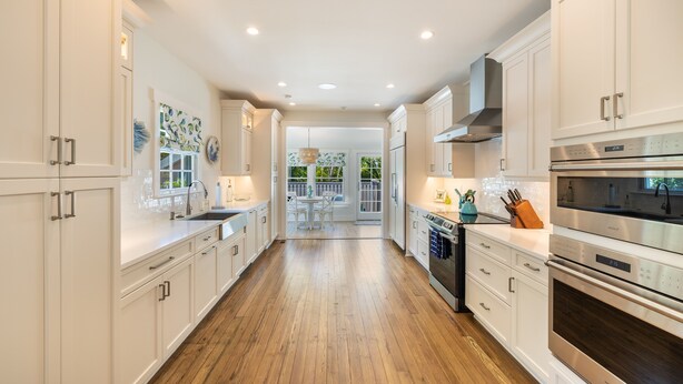 A modern kitchen with white cabinetry, stainless steel appliances, and a wooden floor. - Historic MamaDear House, Boca Grande Island w/private pool, 5min stroll to beach (Boca Grande)