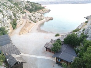 A coastal area with rocky terrain, a sandy beach, and several buildings with metal roofs. - Wohnung Tonka für Einen Ruhigen Urlaub am Meer und Bergen (Karlobag, Cesarica, Ribarica)