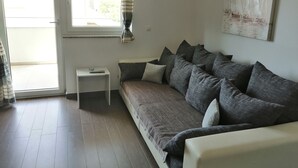 A living room with a sofa, a small side table, and a window with curtains. - Wohnung Tonka für Einen Ruhigen Urlaub am Meer und Bergen (Karlobag, Cesarica, Ribarica)