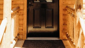 A wooden cabin entrance with a black door, a small window with a grid pattern, and a lantern above the door. - Cozy cabin for up to 6 guests - Hocking Hills - Firepit -Hot Tub - Wifi (Logan)
