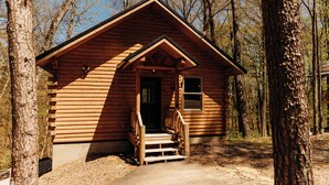 A wooden cabin with a porch and steps leading to the door, surrounded by trees. - Cozy cabin for up to 6 guests - Hocking Hills - Firepit -Hot Tub - Wifi (Logan)