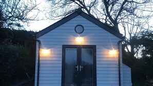 Un petit bâtiment d’un seul étage, doté d’une porte vitrée à cadre sombre et de deux lampes extérieures.