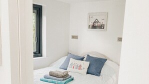 Une chambre à coucher avec un lit, des oreillers, une couverture et une petite fenêtre.