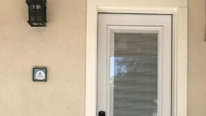 A white door with a glass panel and a small mailbox on the wall.