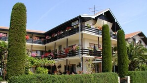 A multi-story hotel with balconies adorned with flowers, a well-maintained hedge, and a clear sky. - Room in Vodice with Balcony, Air condition, WIFI (4826-3) (Vodice)