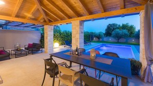 An outdoor dining area with a pool view, stone pillars, and a wooden ceiling. - Villa Lyan with Swimming Pool (Tar Vabriga)
