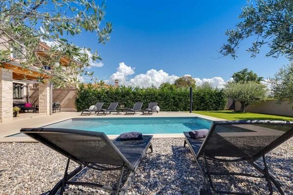 A swimming pool with lounge chairs and a stone wall.